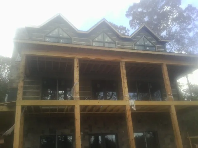 Dormers and porch framing on a large log home under construction — Roof Coating work by our crew in Macks Inn