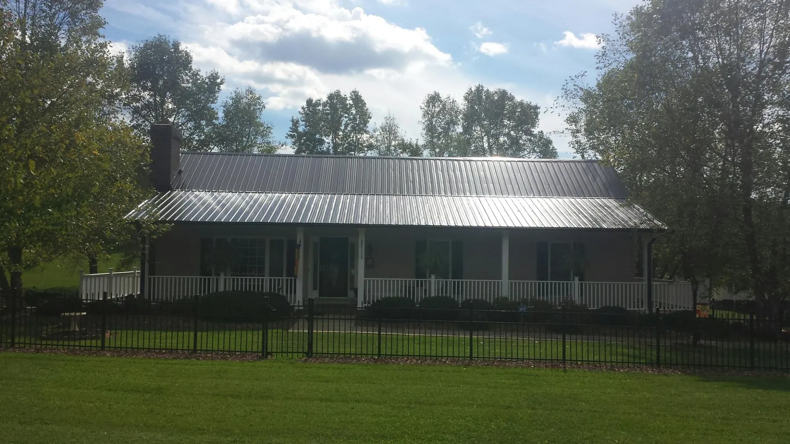 Gray metal roof on a brick ranch with a full width front porch in Macks Inn