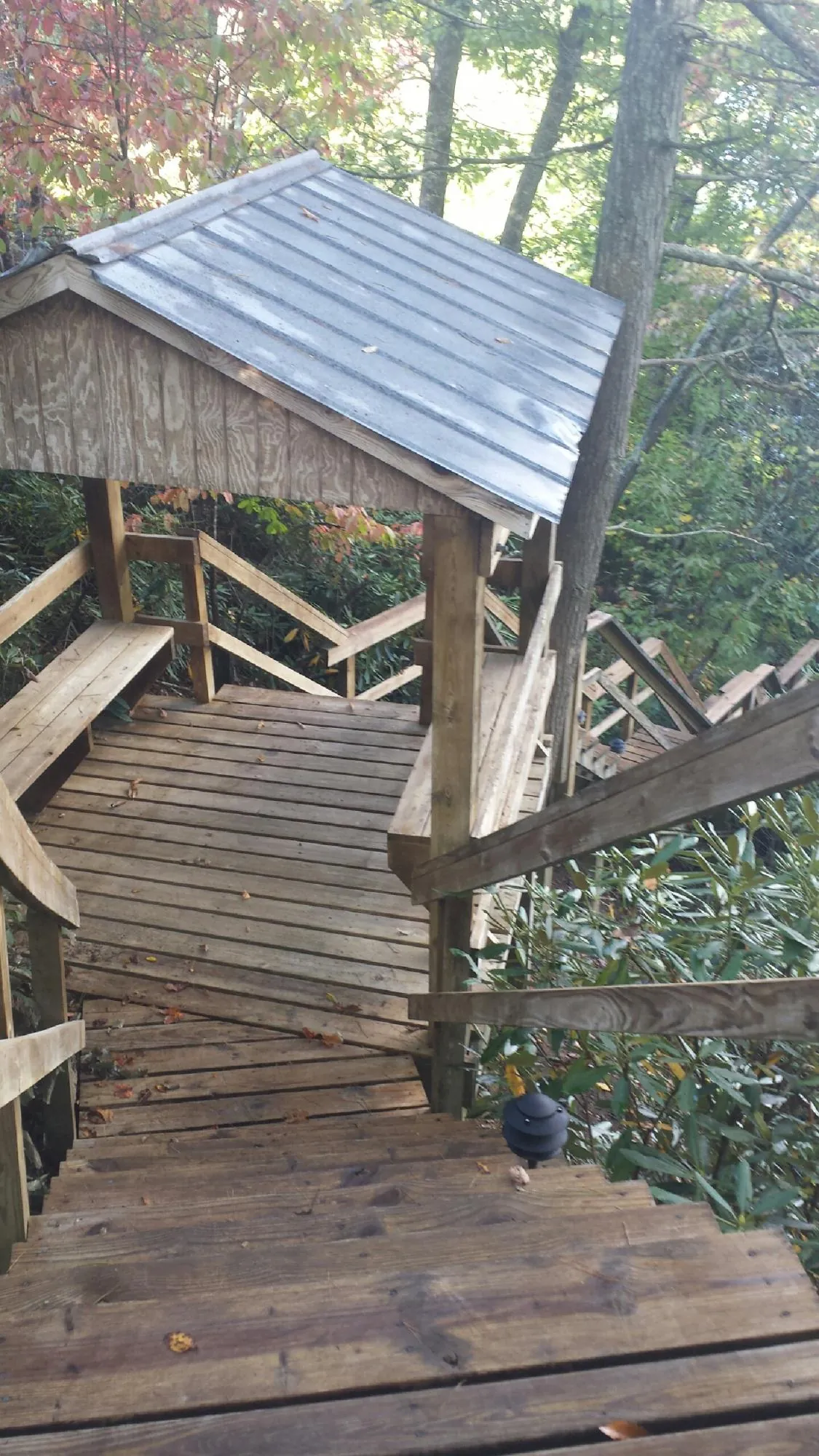 Metal roofed shelter over wooden steps on a wooded walkway — Skylight Repair & Installation work by our crew in Macks Inn
