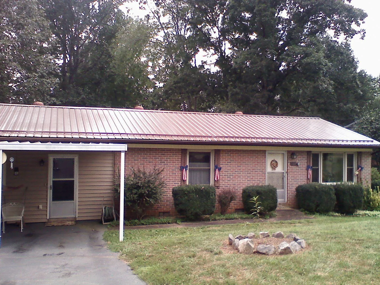 Bronze metal roof and carport on a brick ranch home — Roof Repair work by our crew in Macks Inn