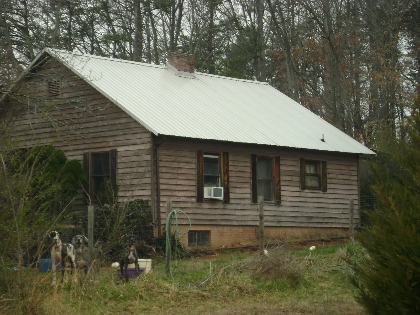 White metal roof on an old wood sided farmhouse, from a Metal Roof Installation job in Macks Inn