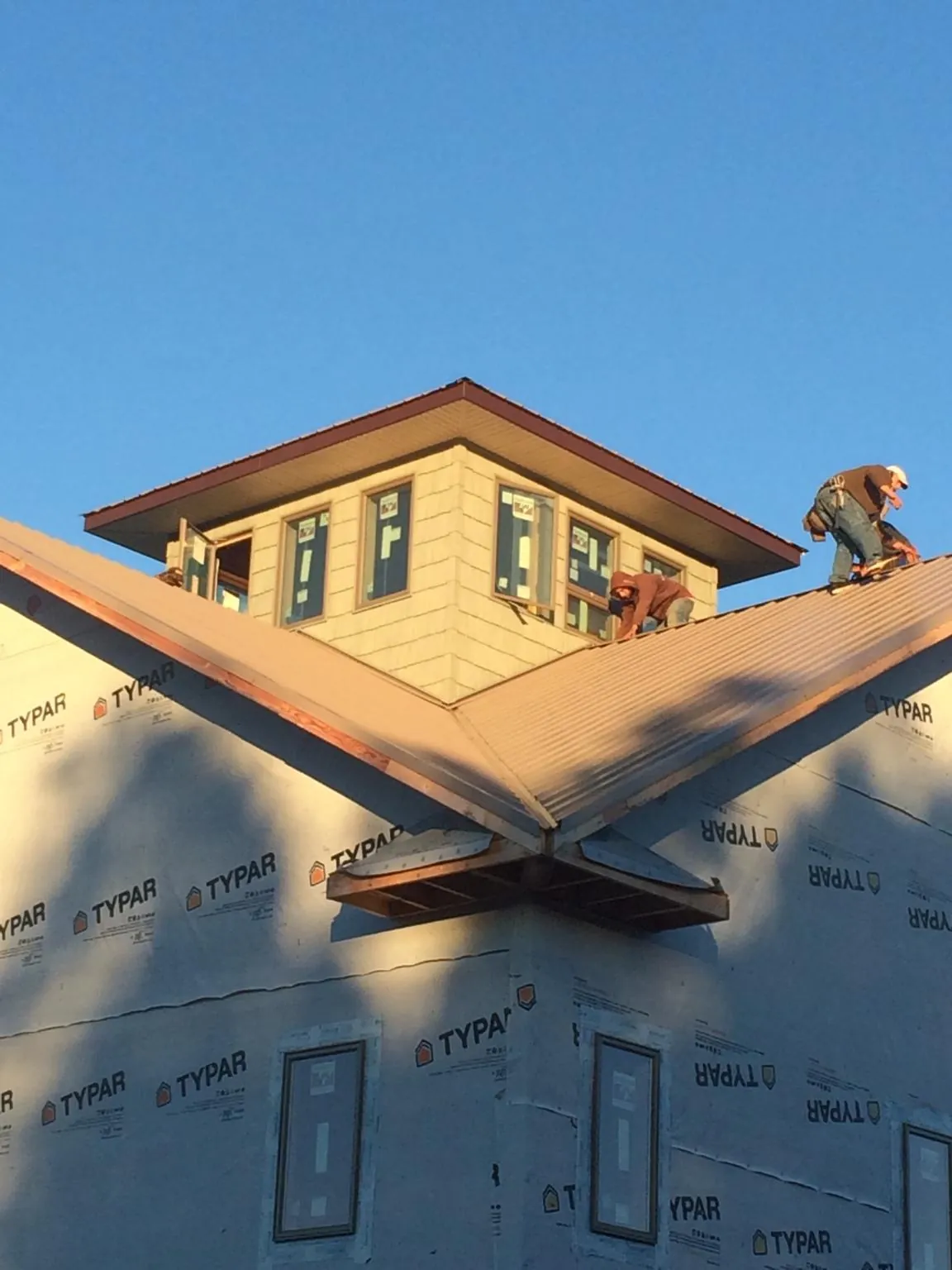 Roofers working around a rooftop cupola on a new metal roof at sunset — Roof Waterproofing in Macks Inn by Roofing Brothers